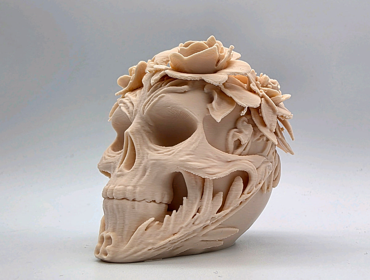 Three-quarter view of floral skull sculpture with leaves around the cheek and jaw