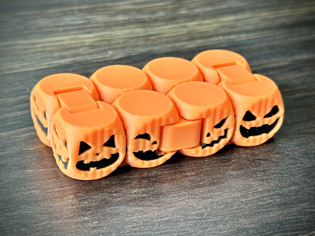 Orange articulated pumpkin fidget chain with varied black jack-o-lantern faces