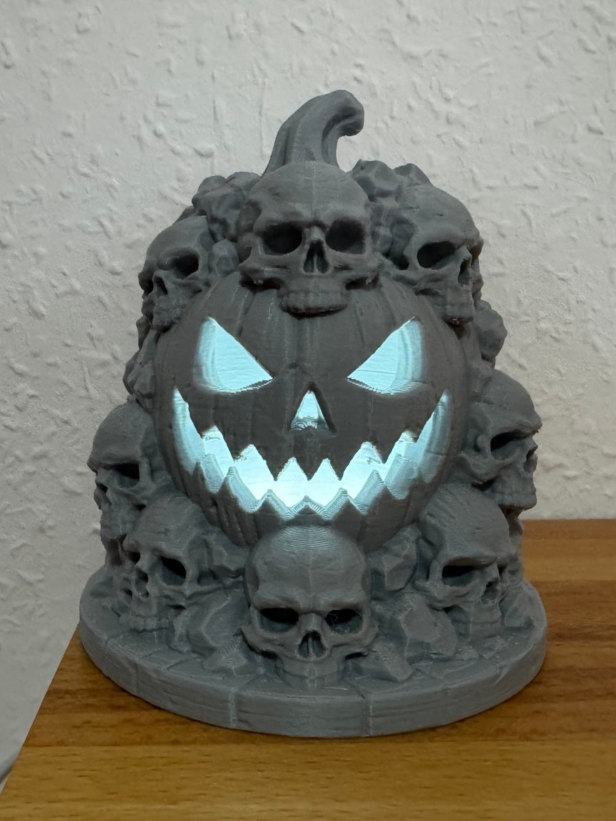 Grey Skull Mountain tealight holder with clustered skulls around a central glowing grinning face on a wooden table
