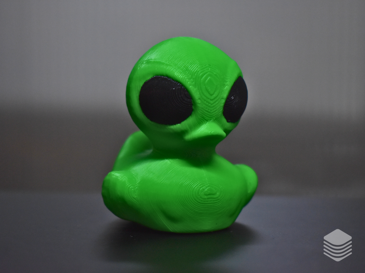 Bright green alien bath duck with oversized black eyes viewed from the front