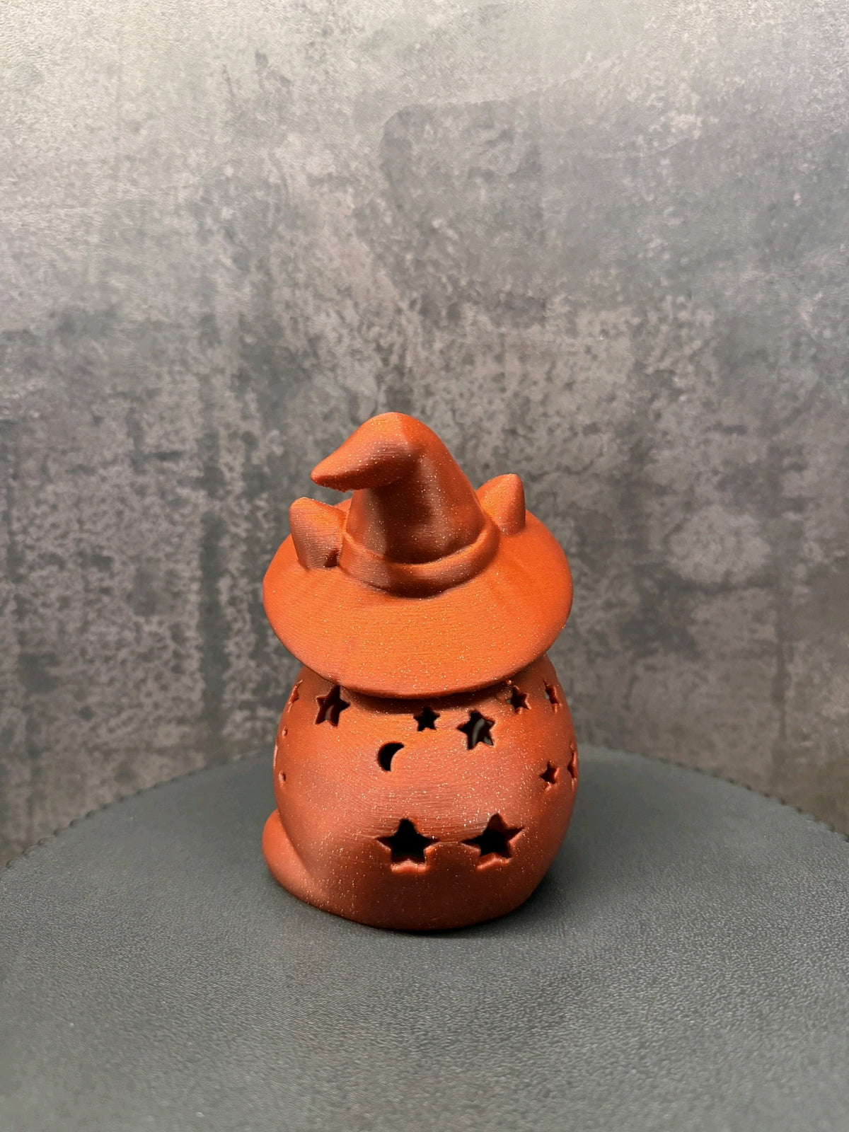 Glowing orange witch-hat cat lantern with a smiling face, paws and star, moon and dot cut-outs