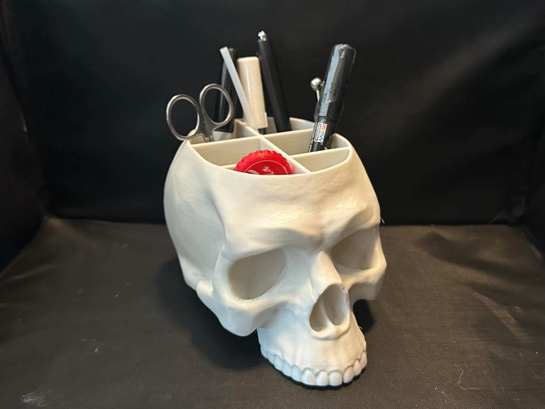 White skull-shaped desk organiser holding pens and scissors