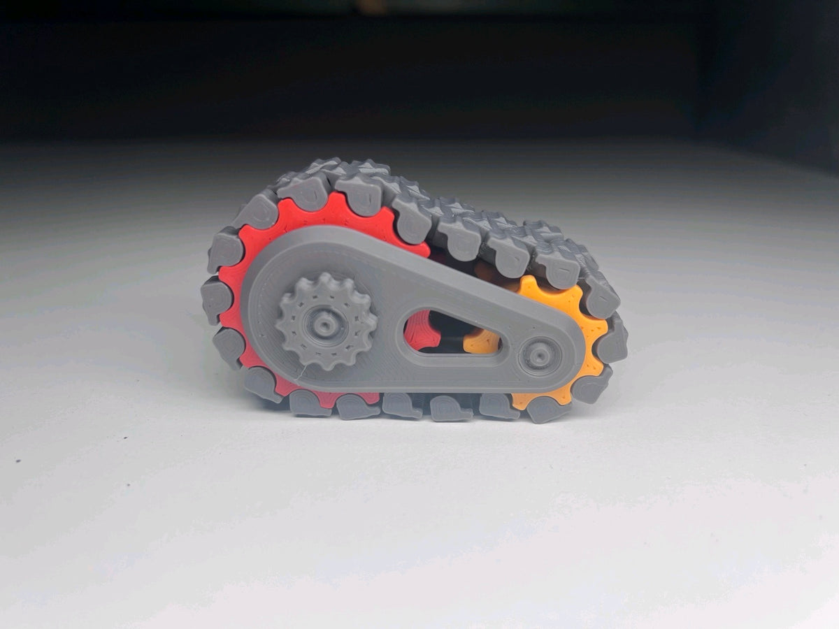 Dark grey linked tread fidget with grey frame and visible coloured gears
