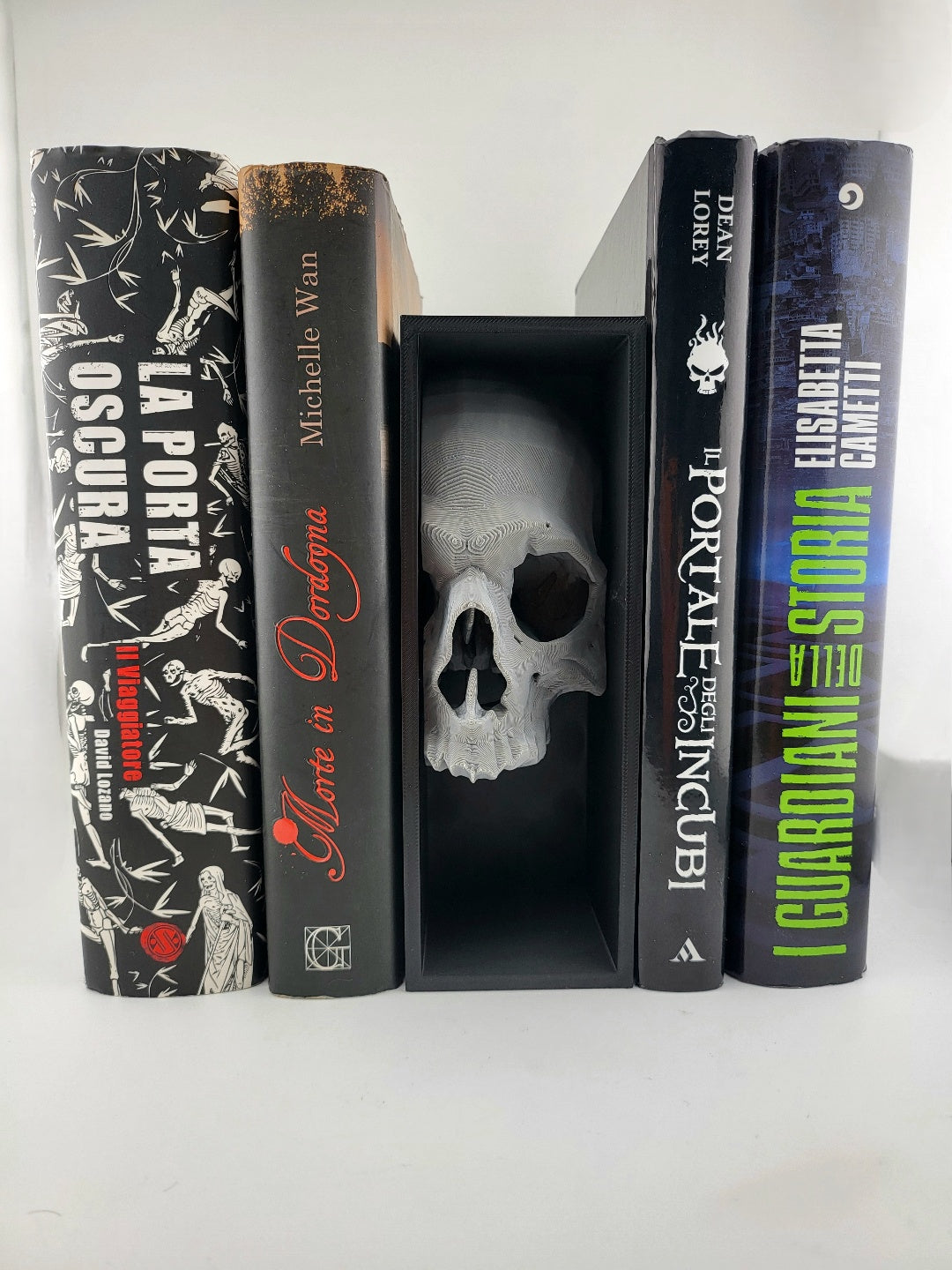 Unpainted skull book nook in a black recessed frame displayed between books