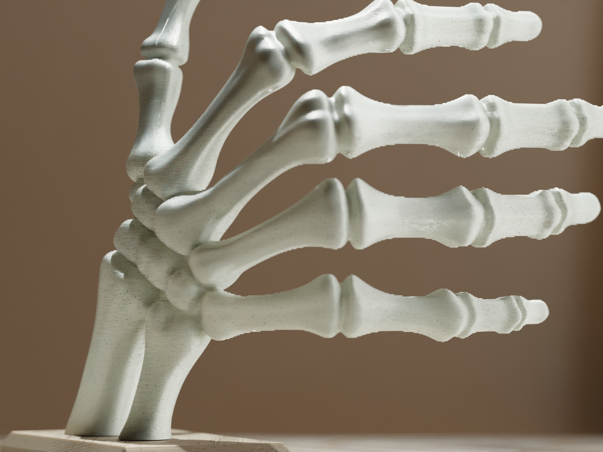 Unpainted skeleton hand sculpture on its rectangular base
