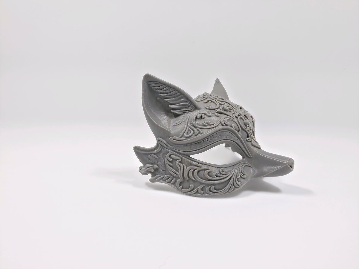 Front view of an ornate grey cat mask with almond-shaped eyes and floral scrollwork