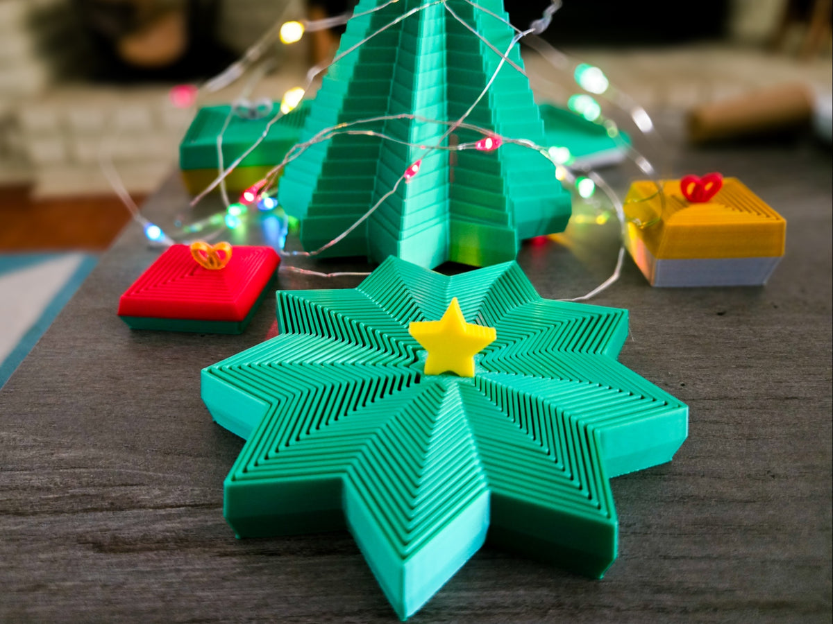 Star-shaped fidget spinner with a yellow centre star in front of a lit Christmas tree