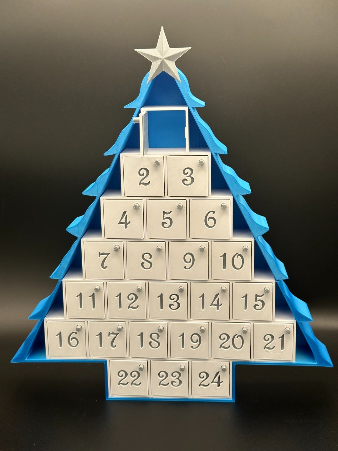 Blue tree-shaped Advent calendar with 24 numbered drawers and a star topper