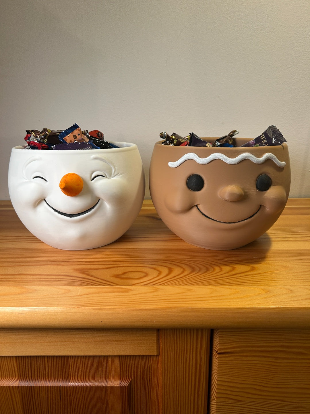White and brown snowman-head snack bowls filled with wrapped sweets