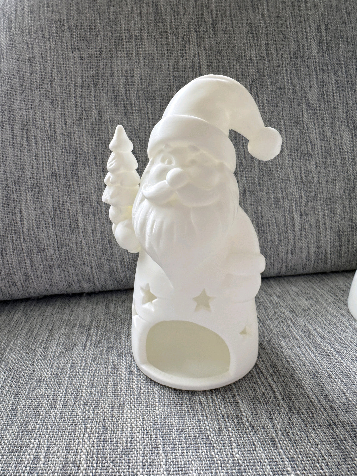 White Santa holding a small Christmas tree on a tealight holder