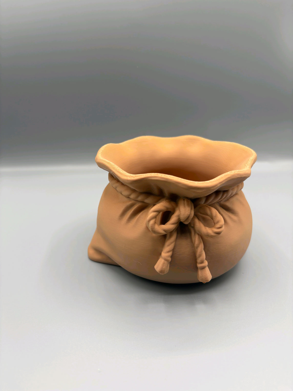 Tan sack-shaped sweet bowl showing its open scalloped rim and rope detail