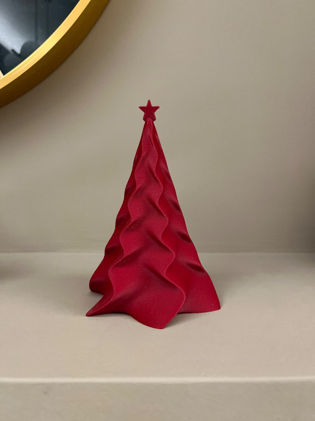 Red sculpted Christmas tree with matching star topper on a shelf