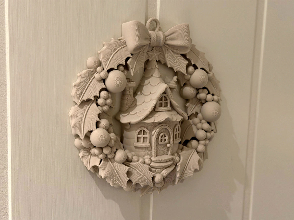 Close-up of the fairy cottage, bow, leaves and berries on the sculpted Christmas wreath