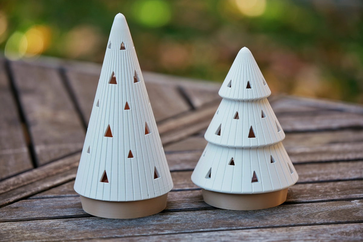 Pair of tall and tiered ribbed Christmas tree tealight holders with fixed beige bases on a garden table