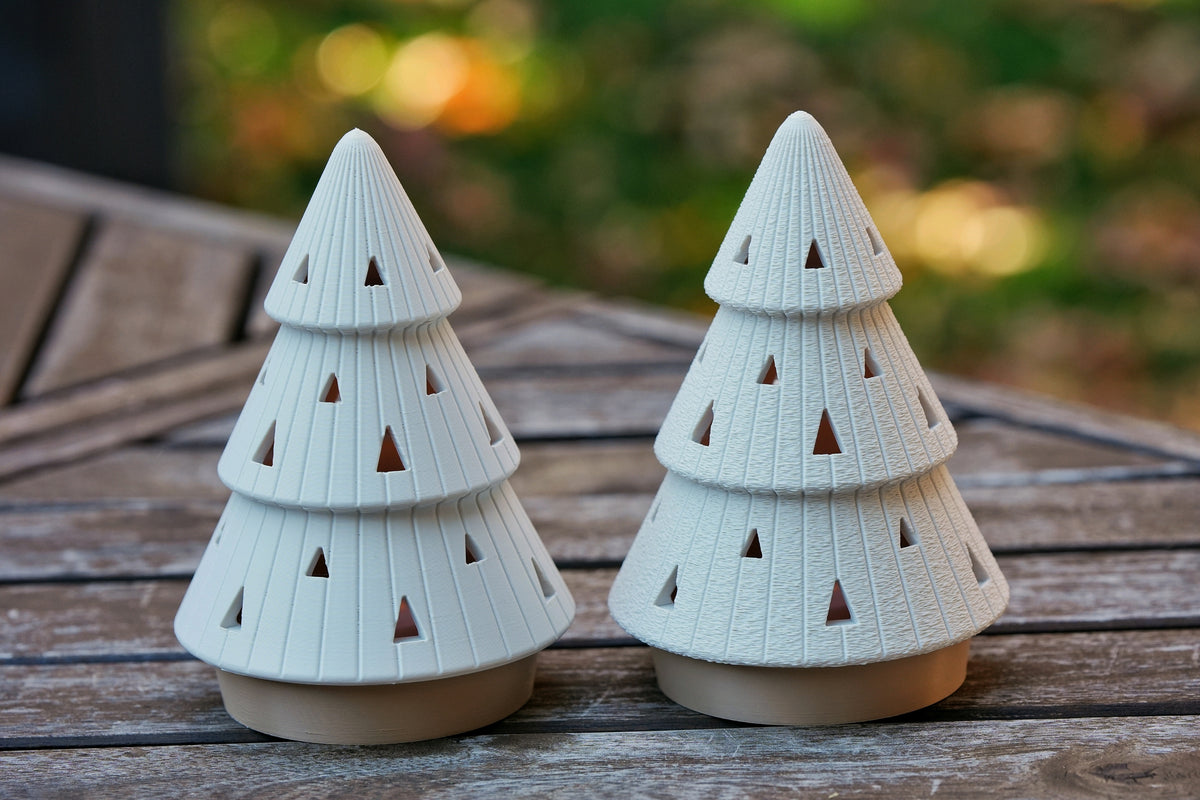 Two white ribbed Christmas tree tealight holders, one tall cone and one tiered tree, with beige bases