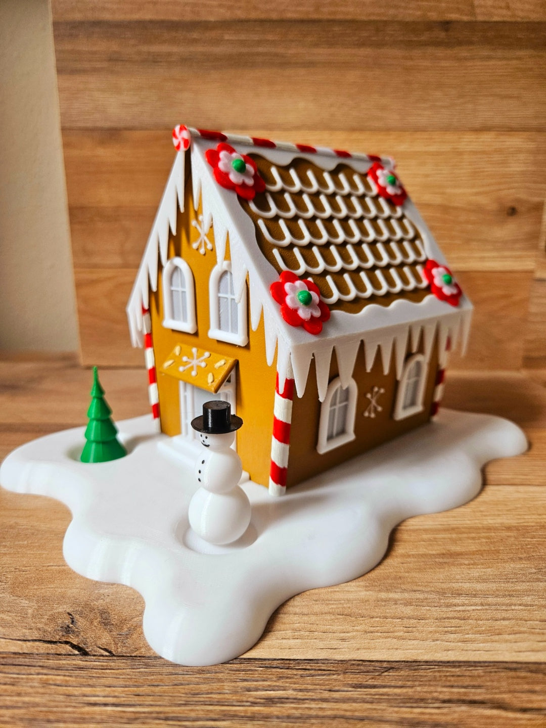 Front view of the snowy gingerbread cabin tealight holder with a snowman and tree
