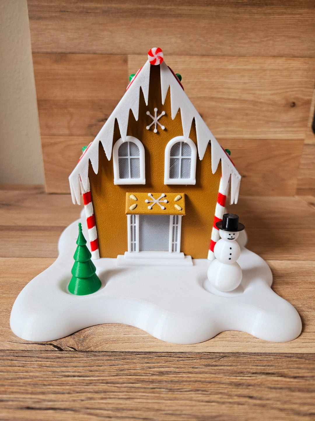 Gingerbread cabin tealight holder glowing through its windows in a dim setting