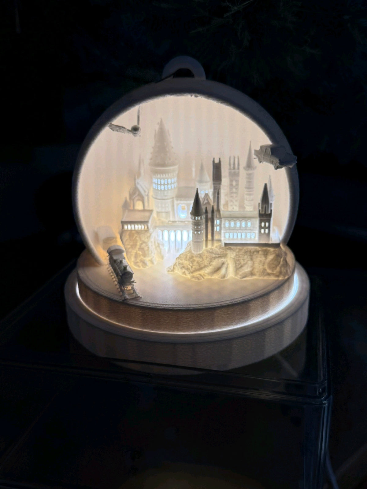 Illuminated miniature cathedral skyline and train within a white rounded frame