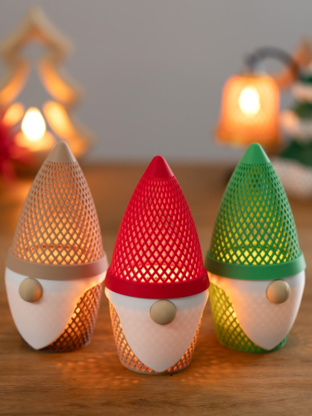 Set of three beige, red and green gonk tealight holders glowing warmly in a Christmas setting