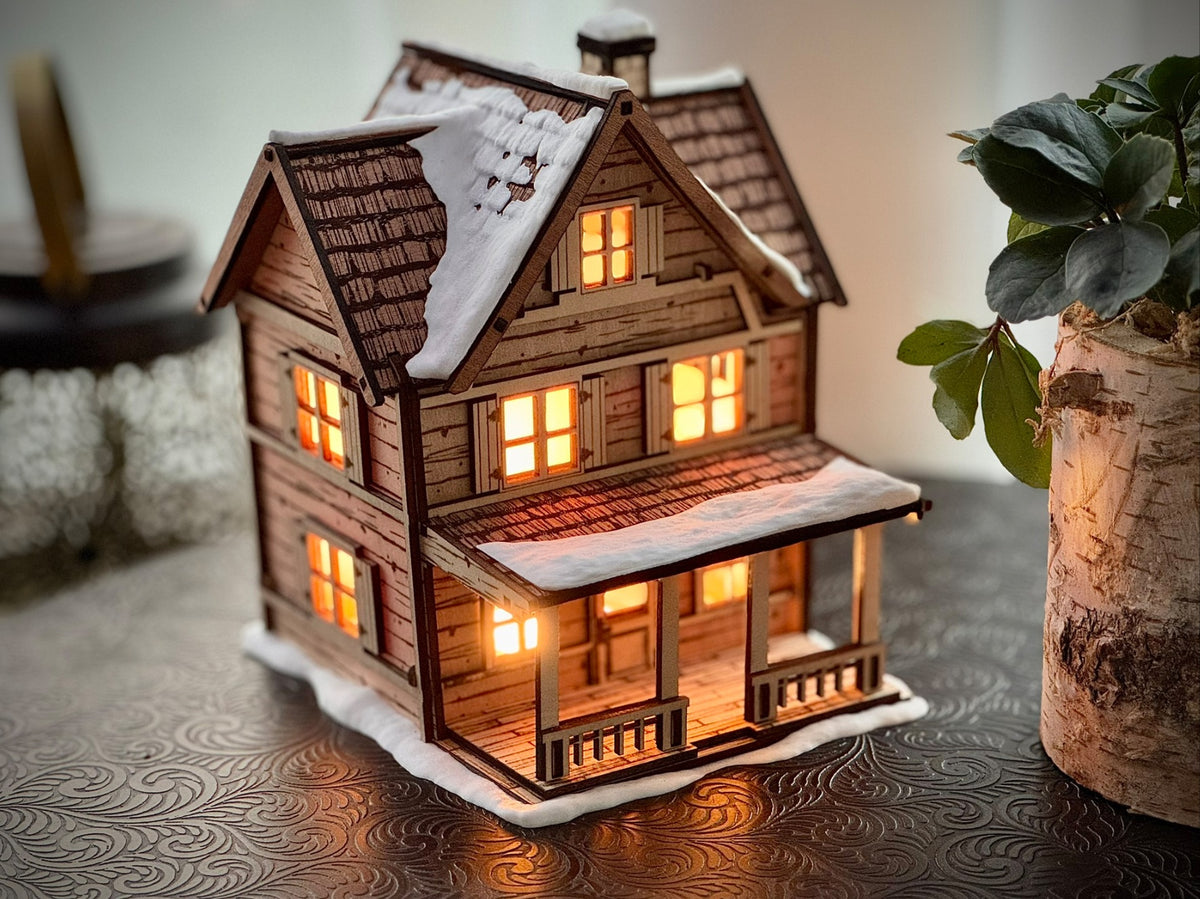 Snowy multi-gabled Tealight House with glowing windows and a covered porch