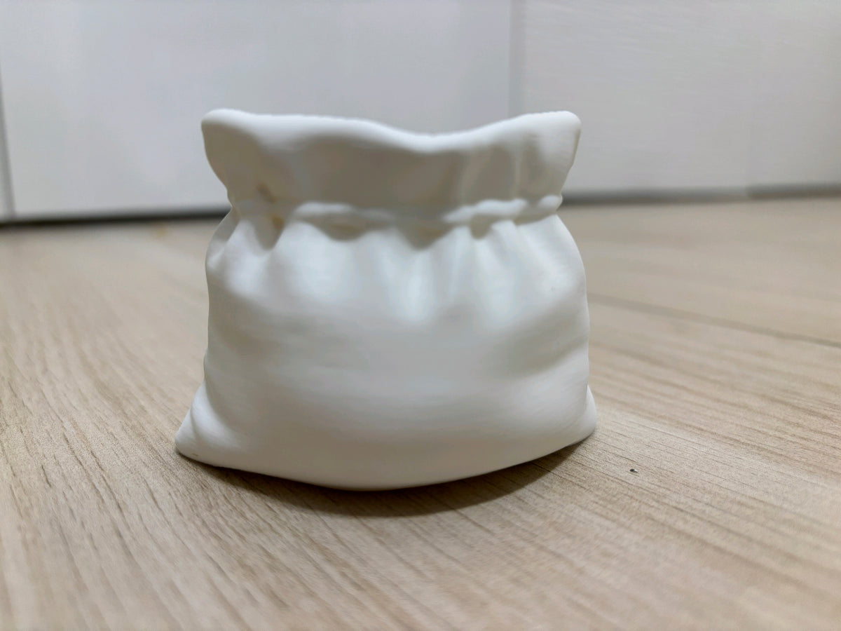 White sack-shaped planter showing its open wavy rim and sculpted folds
