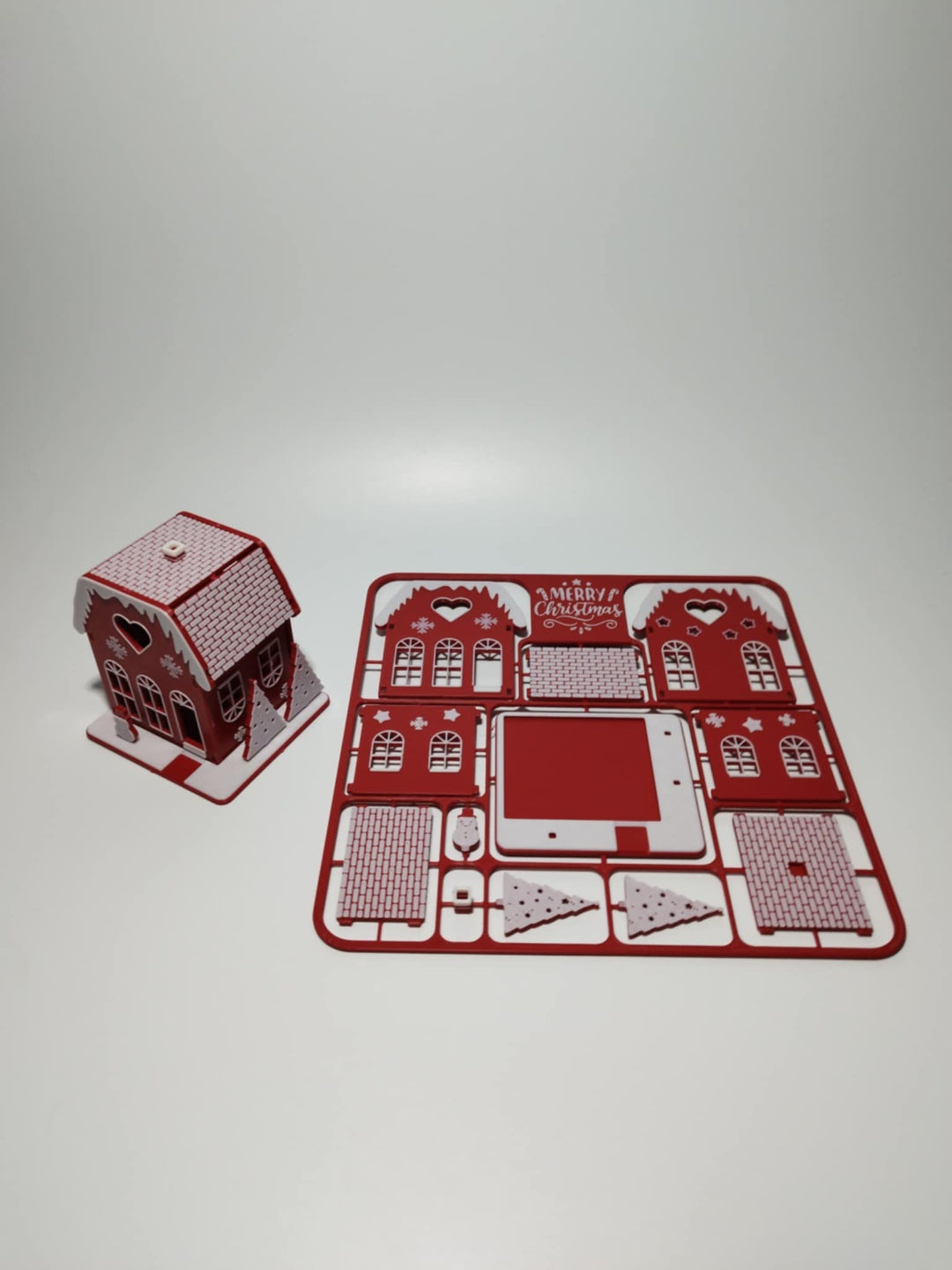 Flat house kit components displayed beside the assembled red and white house