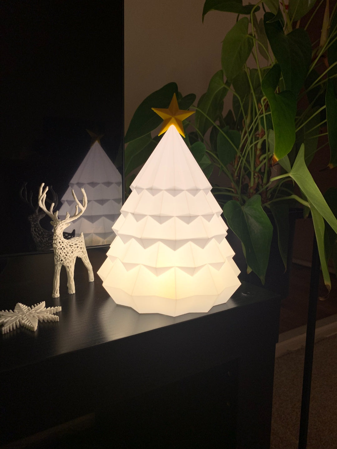 White faceted Christmas tree tealight holder with gold star topper styled beside a reindeer ornament