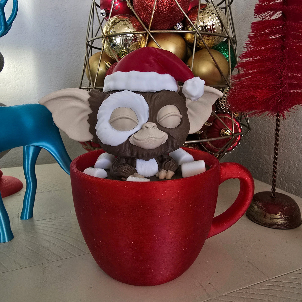 Close view of Gizmo wearing a Santa hat in a red Christmas mug