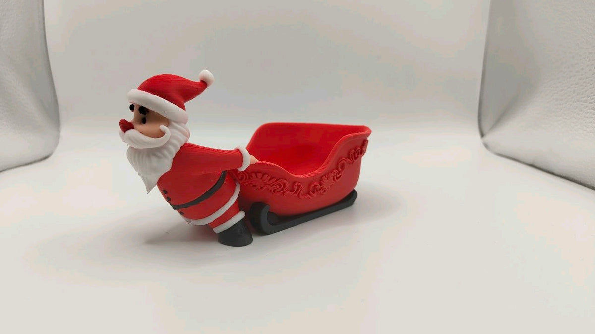 Studio view of the Santa figure and open red sleigh sweet bowl with decorative scrollwork and black runners