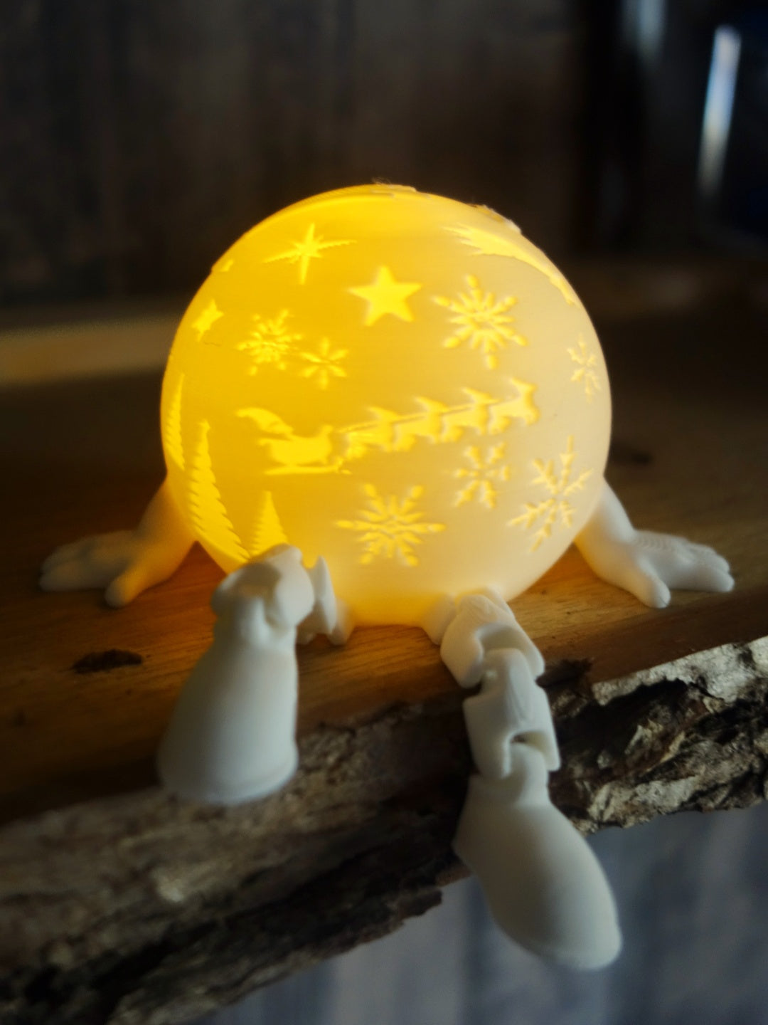 White snow-globe-style tealight holder glowing warmly, with raised stars and snowflakes, a train detail and short legs
