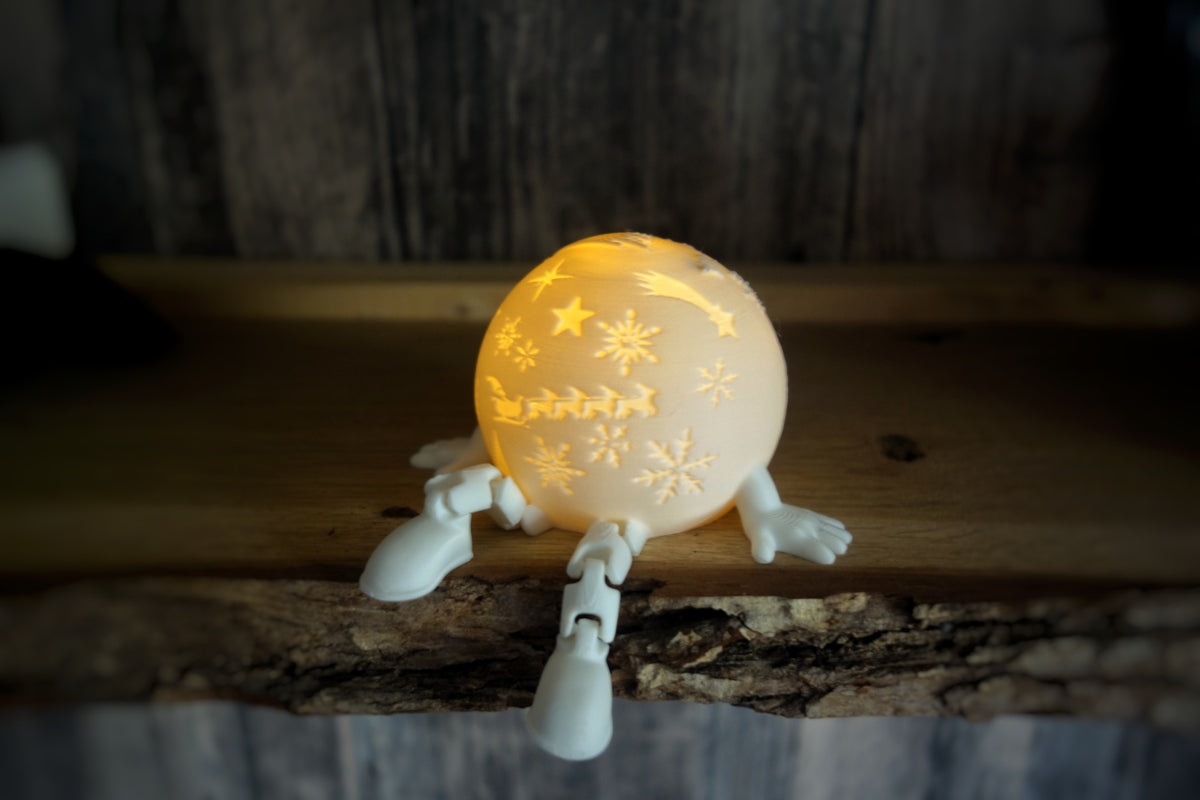 White snowflake-patterned globe tealight holder with short legs and a miniature train motif