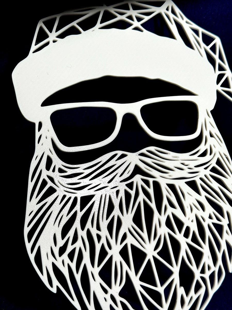 White geometric Santa face sign displayed on a dark wall beside a Christmas tree
