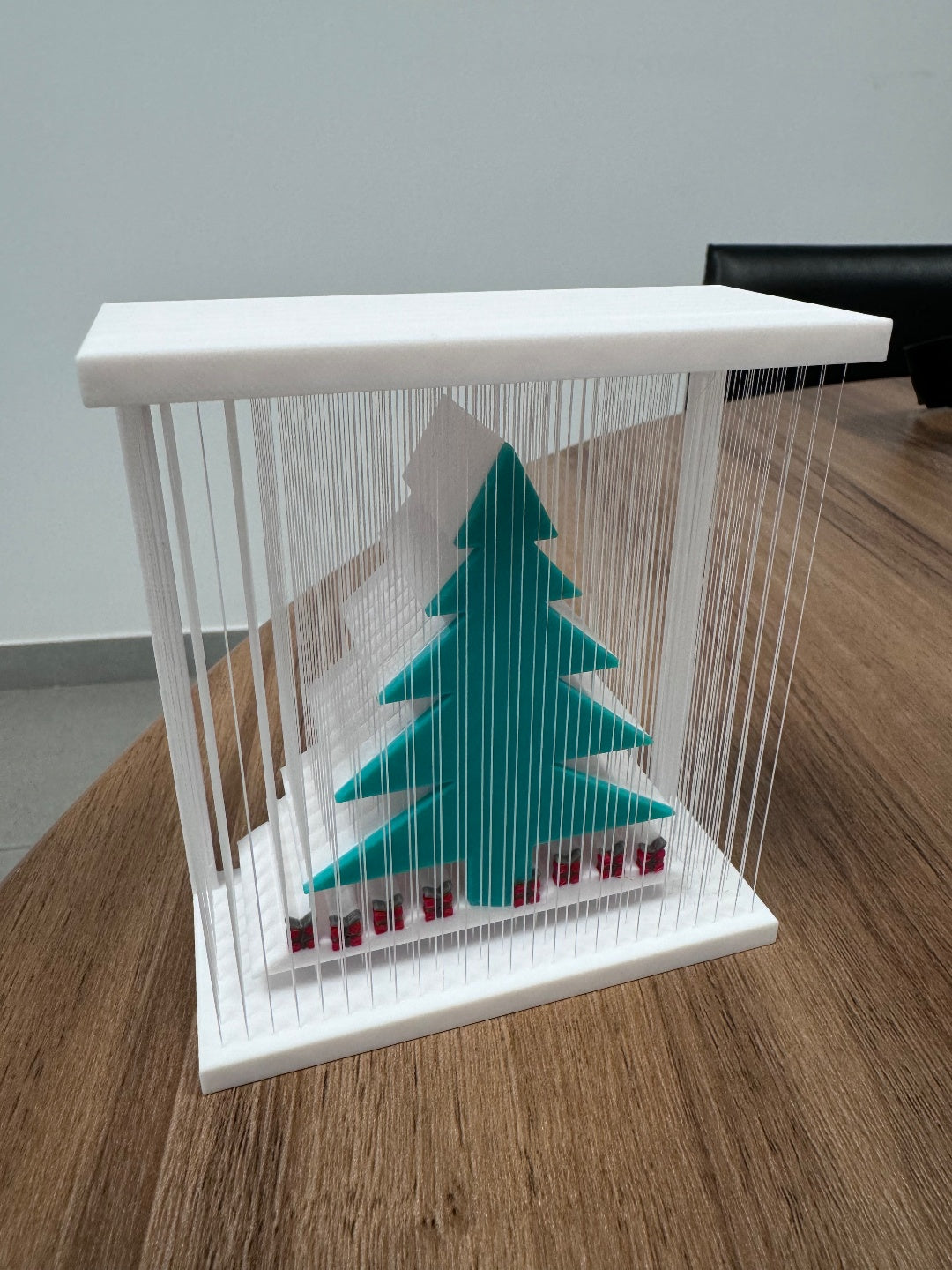 Second angle of the teal-green tree display in a white frame with fine vertical strands and small red-and-dark base accents.