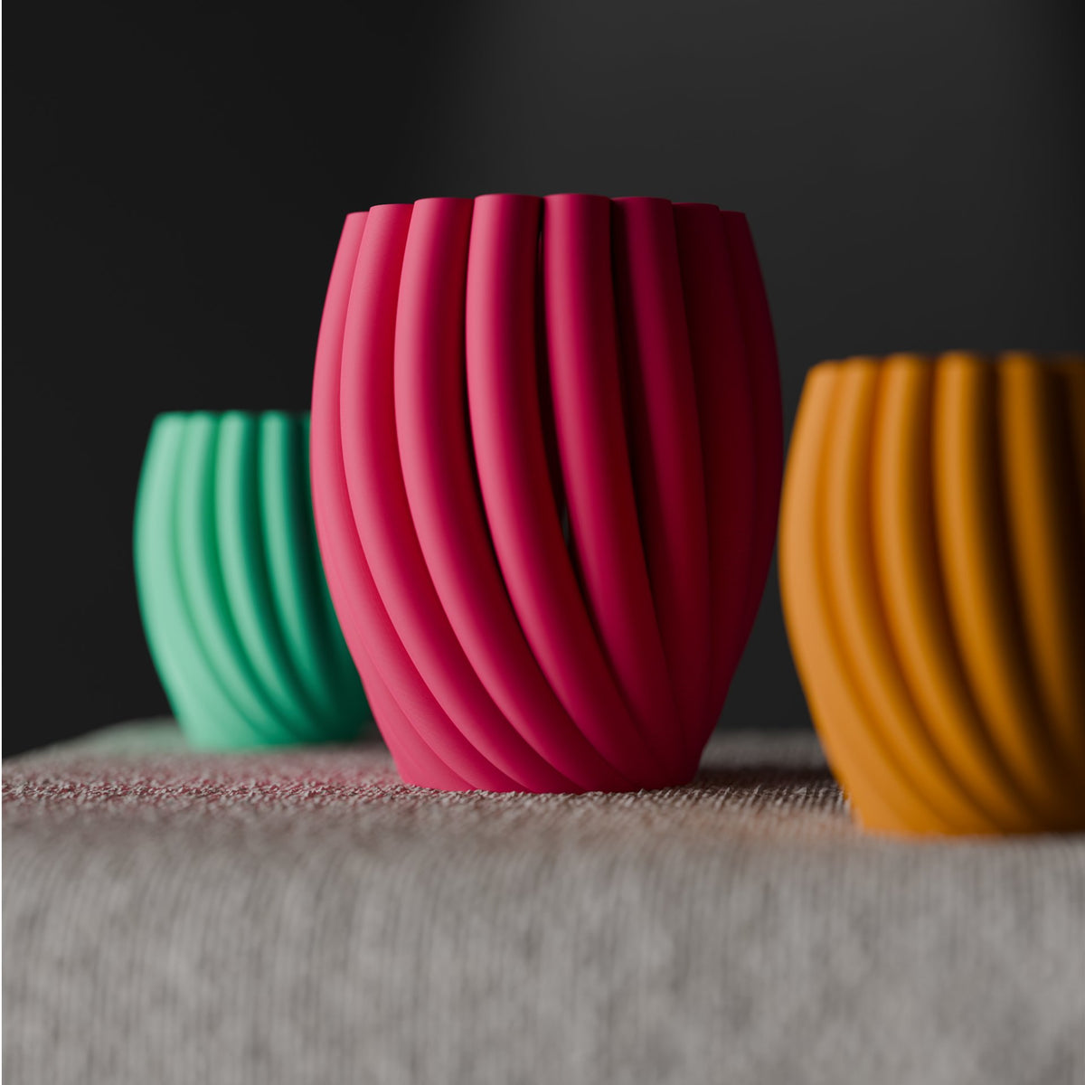 Twist Wave Decorative Vase hot pink mint green mustard yellow three vases overlapping petal-arch spiral ribs draped linen plinth dark studio angled portrait
