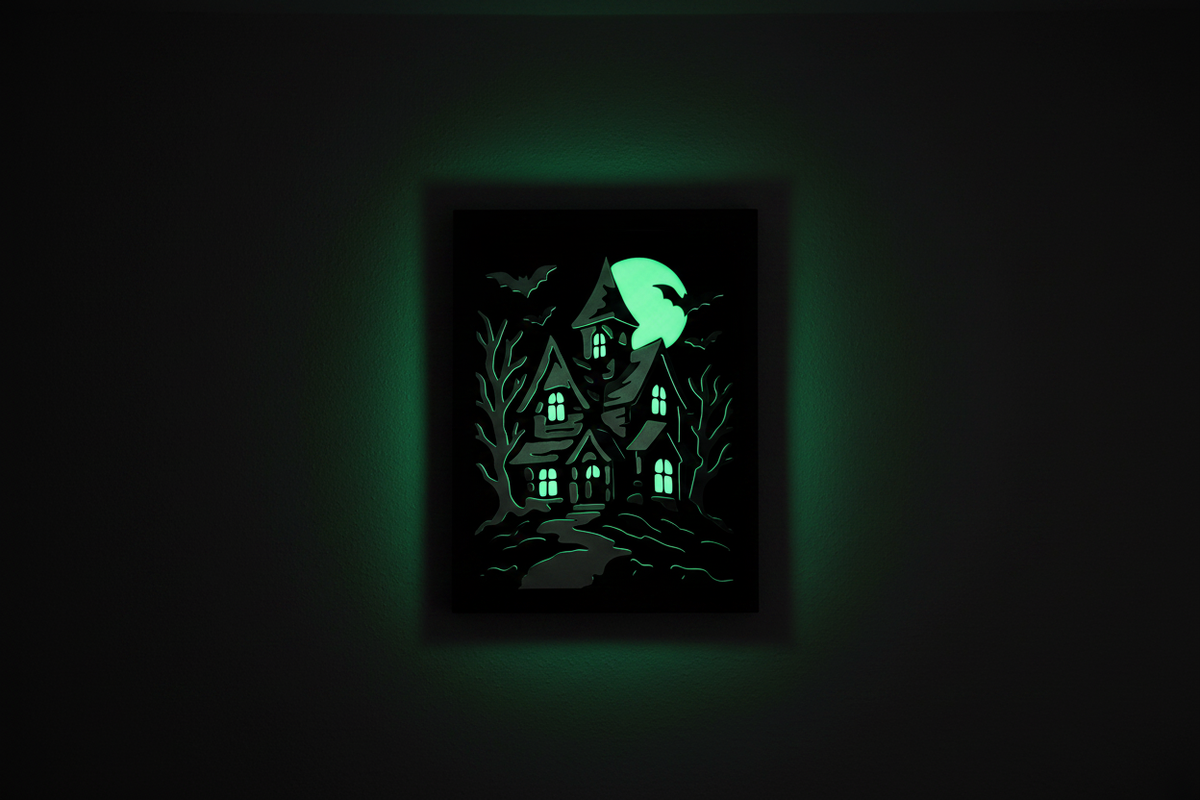 Halloween in Layers: The Haunted Manor shadow box glow-in-the-dark feature illuminating a dark room with vivid eerie green light from windows and moon