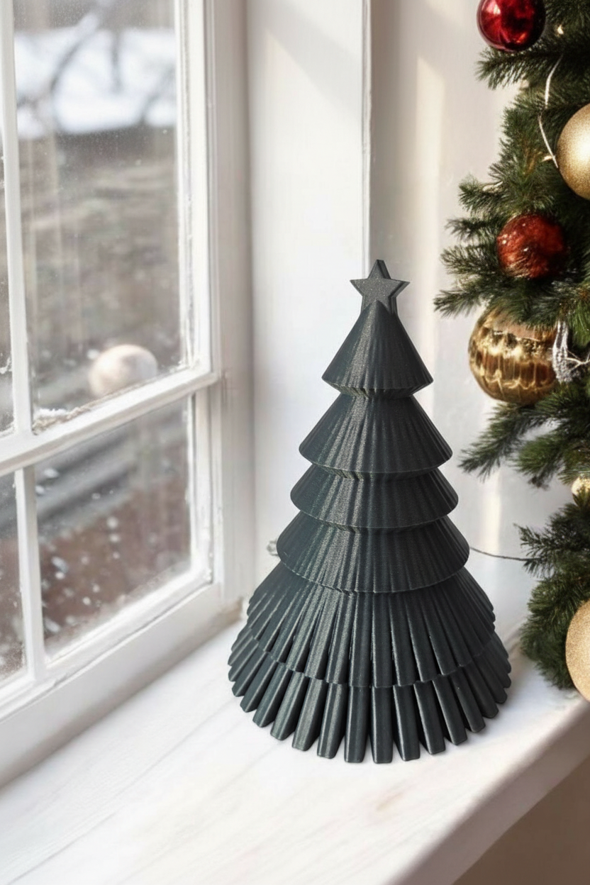 Dark ribbed Christmas tree on window sill beside real Christmas tree with gold baubles