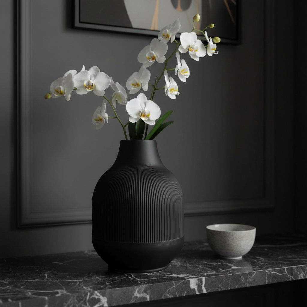 Matte black ribbed vase with white orchids on a marble shelf