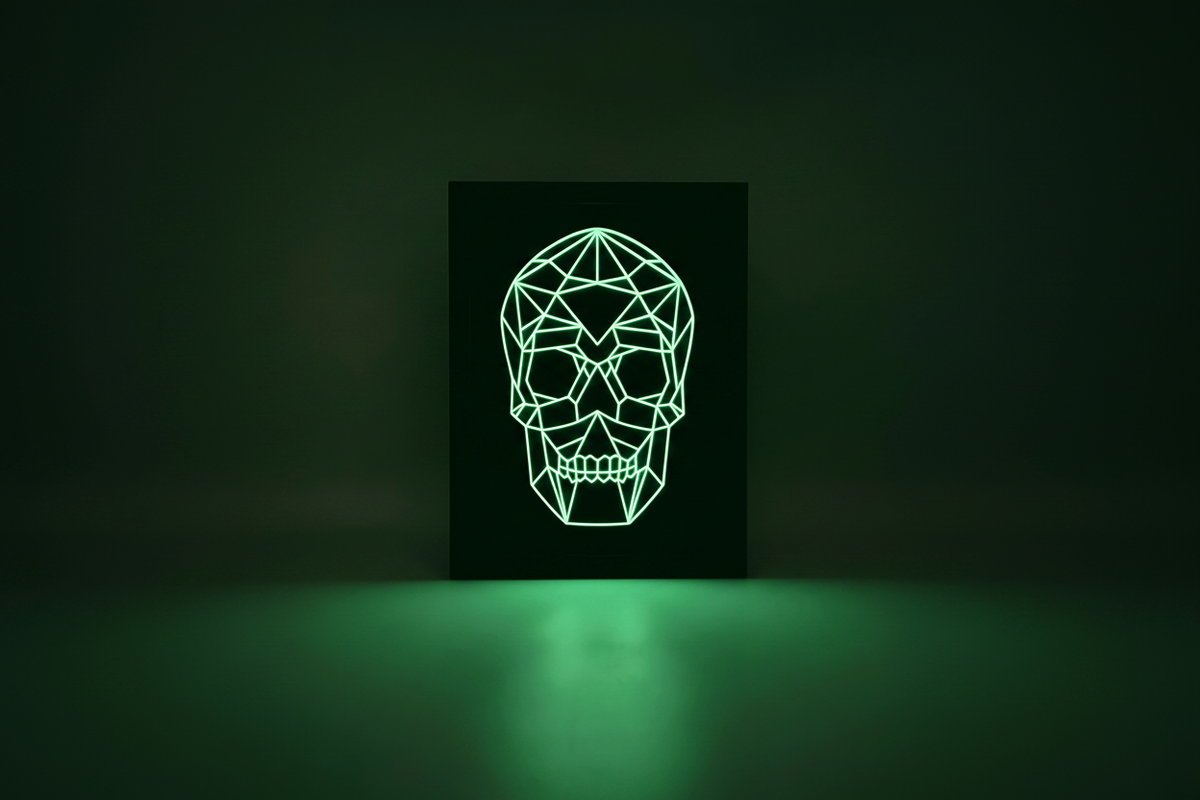 Geometric Glow-in-the-Dark Skull shadow box in a completely dark room glowing vivid bright green and casting an eerie pool of light beneath