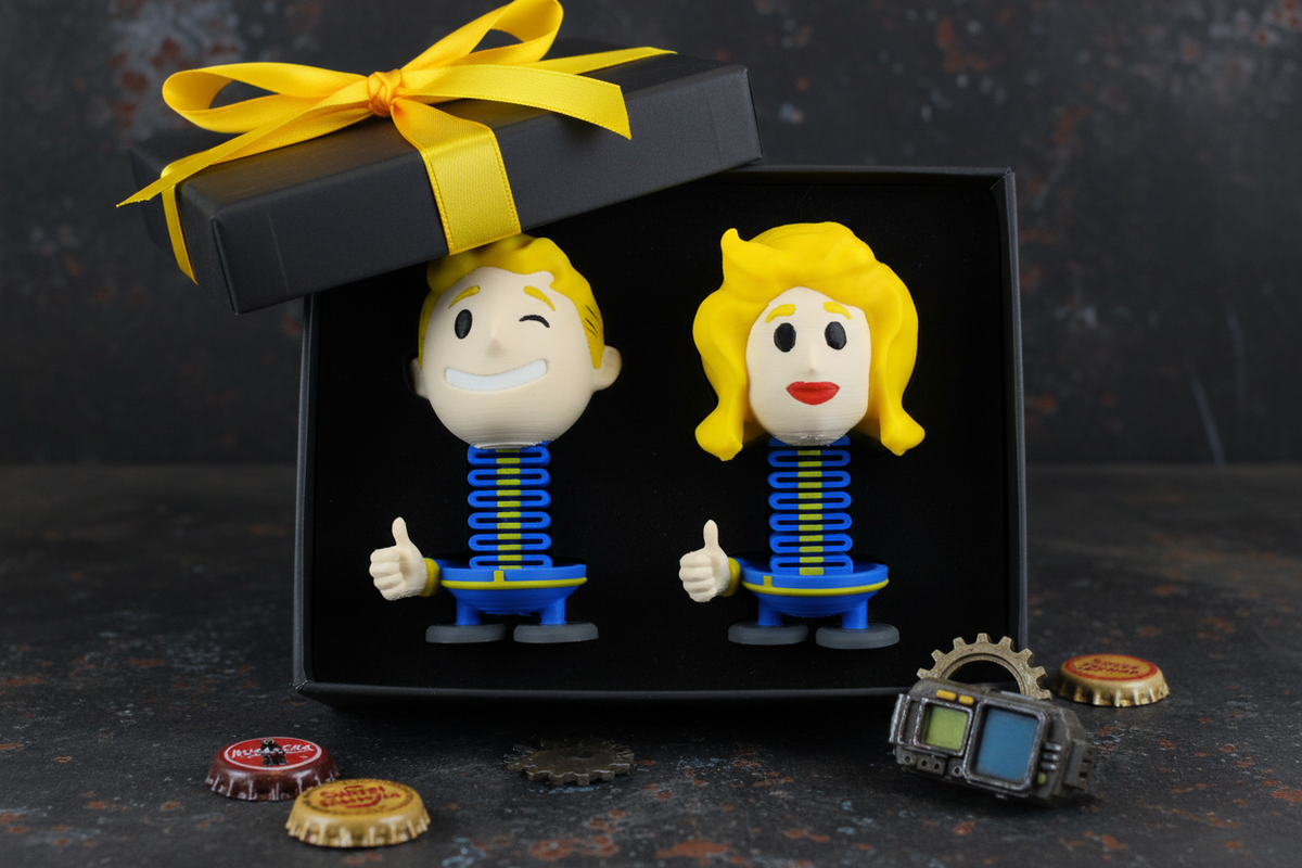 Fallout Vault Boy and Vault Girl Springie set presented as a gift in a matte black box with yellow ribbon and Fallout gaming themed decorations