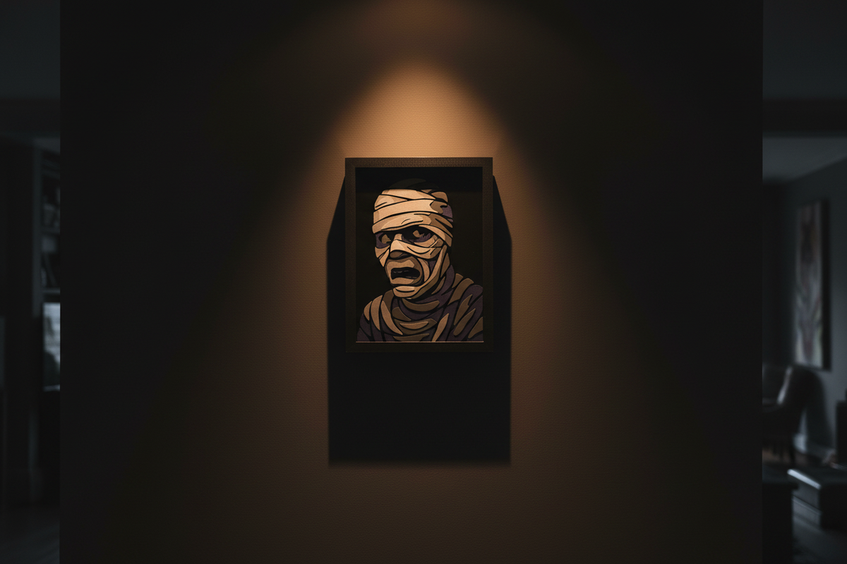 The Mummy Shadow Box hung on a dark charcoal feature wall with warm amber tomb-like spotlight