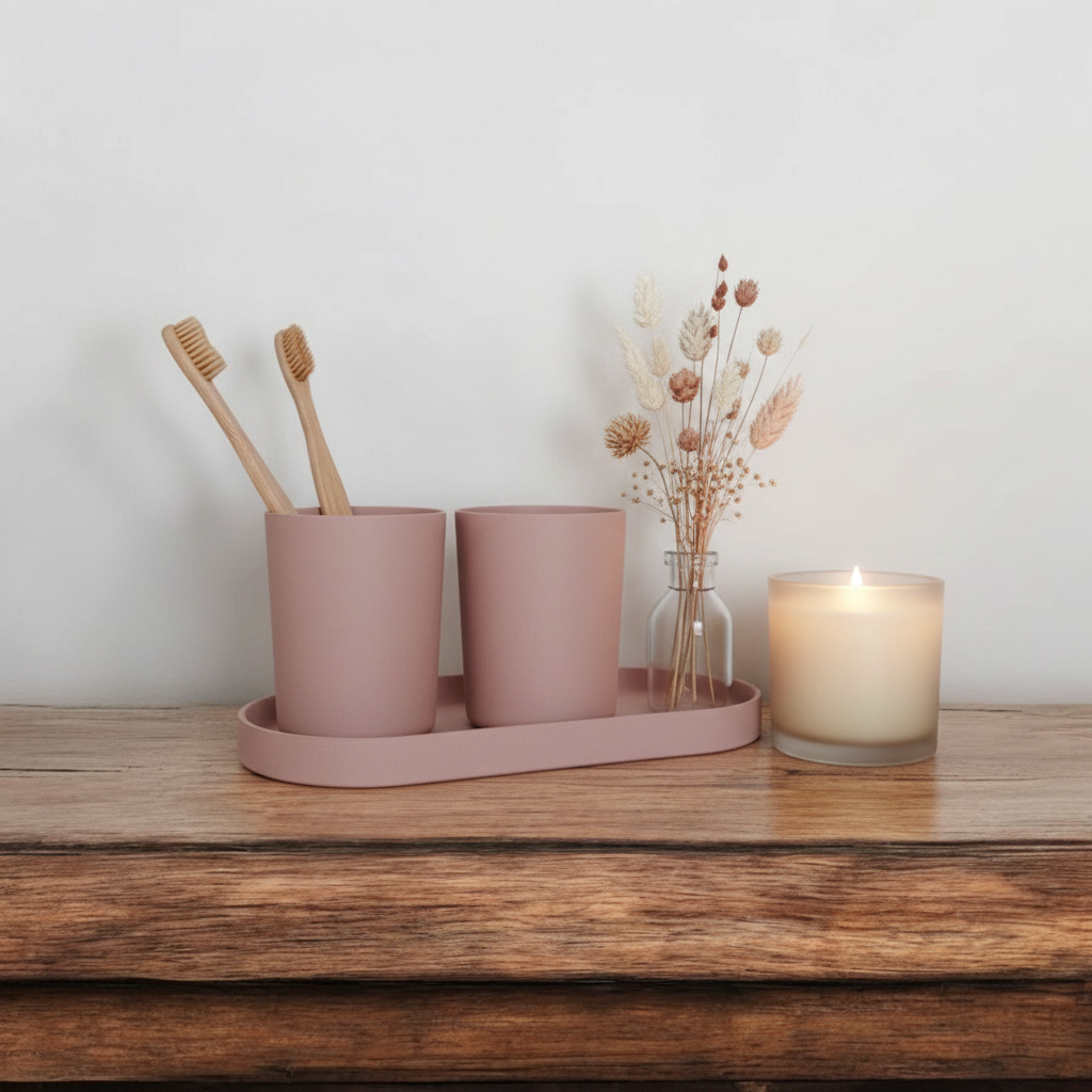 Dusty pink calm sink set on wooden bathroom shelf with bamboo toothbrushes, scented candle and dried flowers