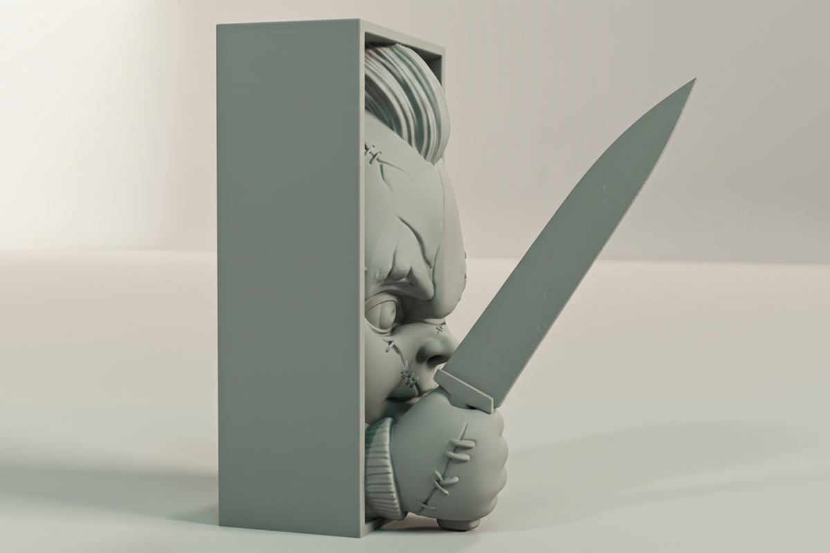 Chucky book nook relief sculpture grey framed box side profile close up full three dimensional depth rectangular box frame rounded doll face emerging knife blade extending dramatically beyond frame neutral studio raking side light landscape editorial