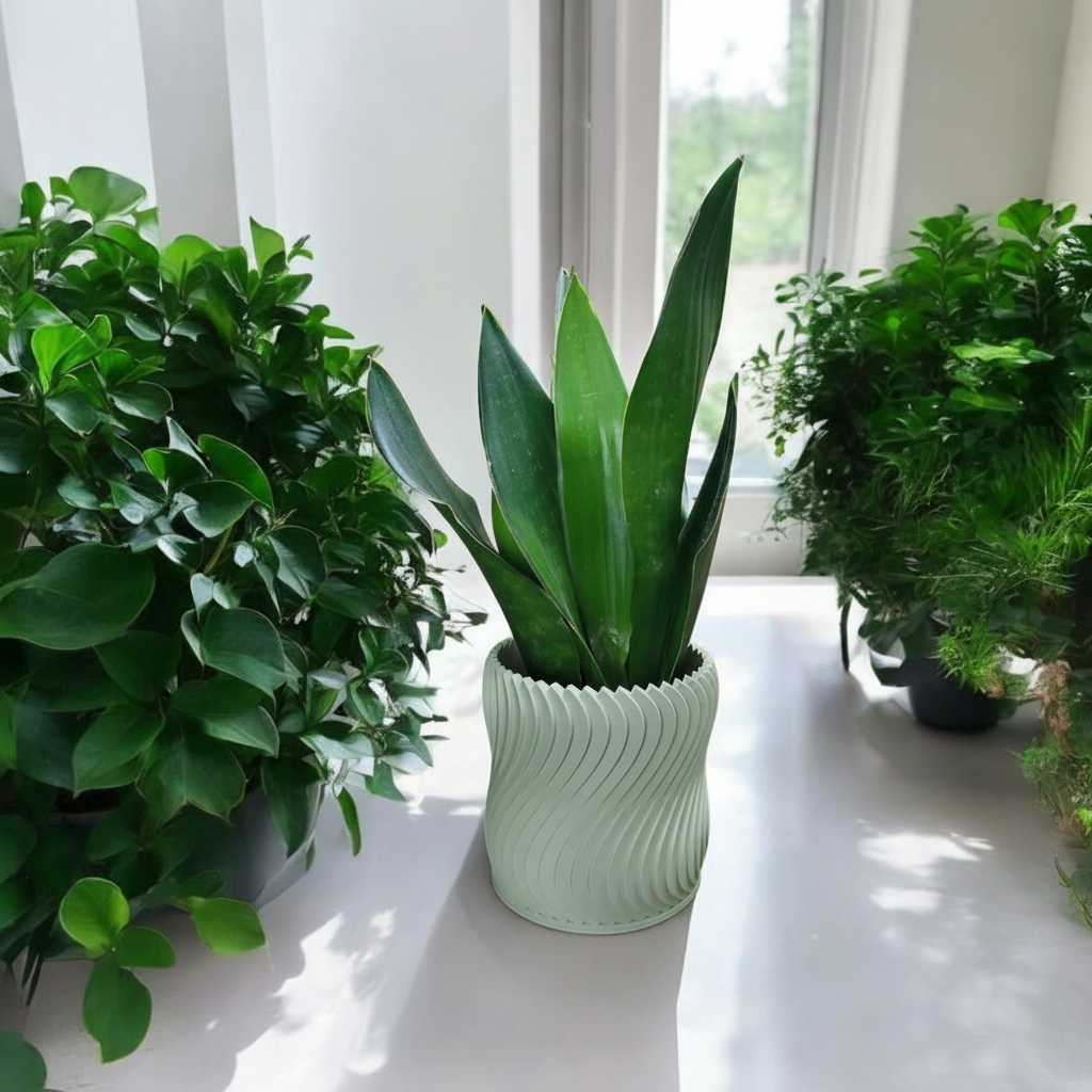 Sage green turbine wheel planter with a snake plant on a bright white windowsill surrounded by lush green plants