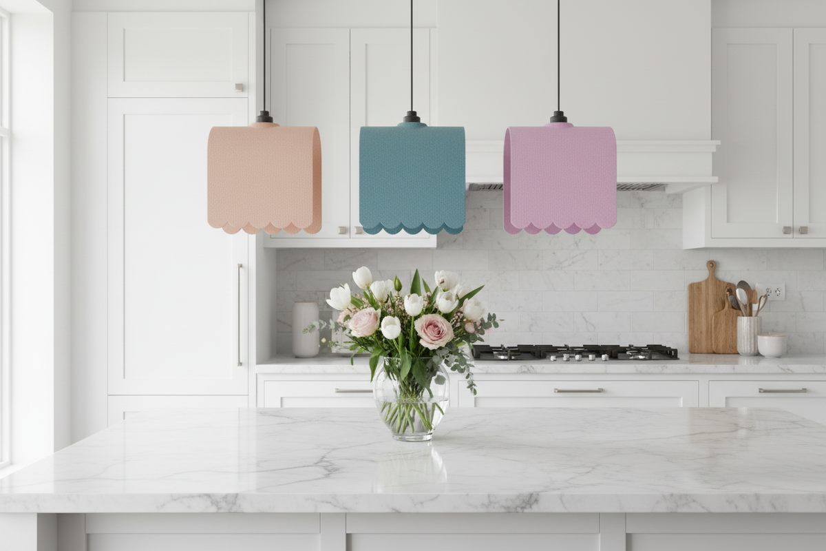 Three awning pendant lampshades in pink, teal and lilac above a marble kitchen island