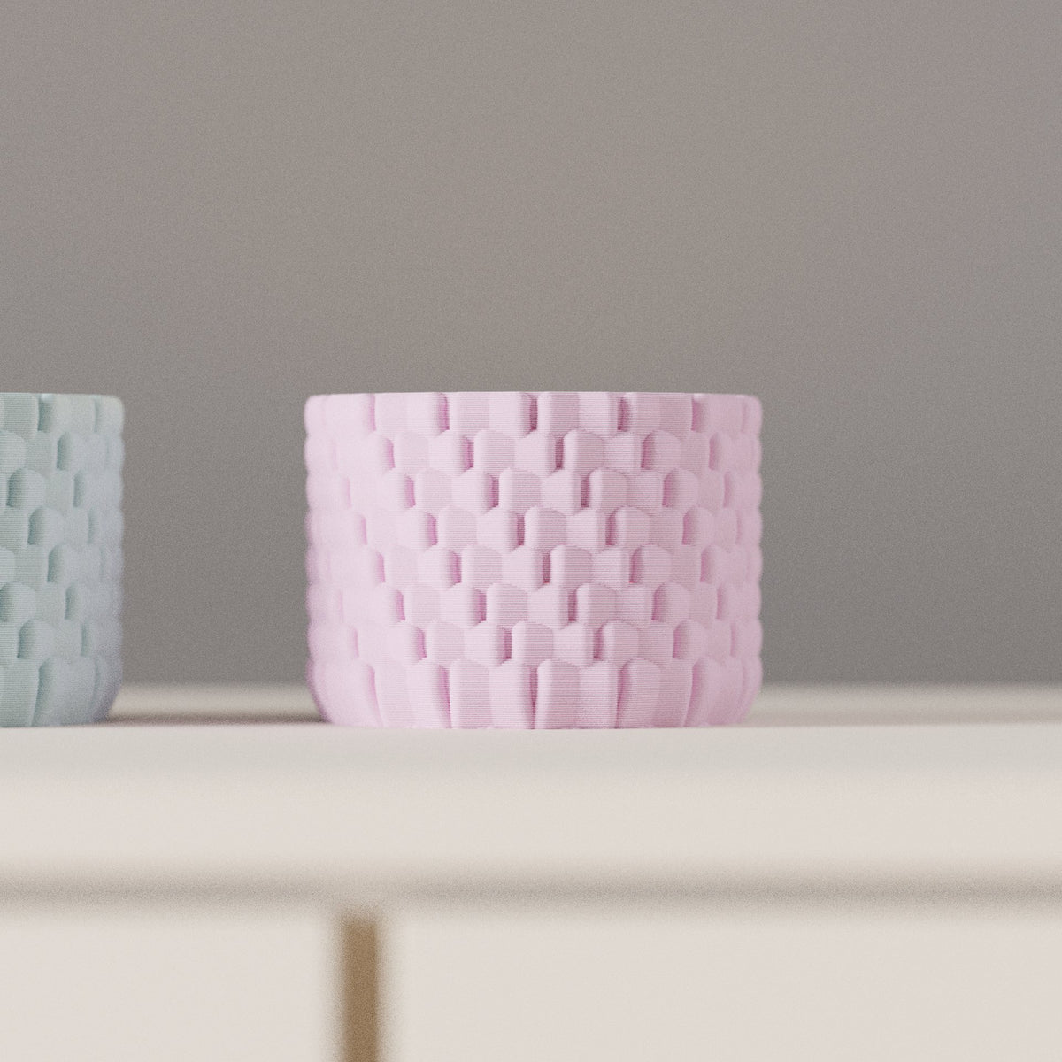 Woven Texture Tealight Holder lavender pink wide low cylinder interlocking raised arch tile woven basket-weave surface pattern on pale sideboard grey wall portrait