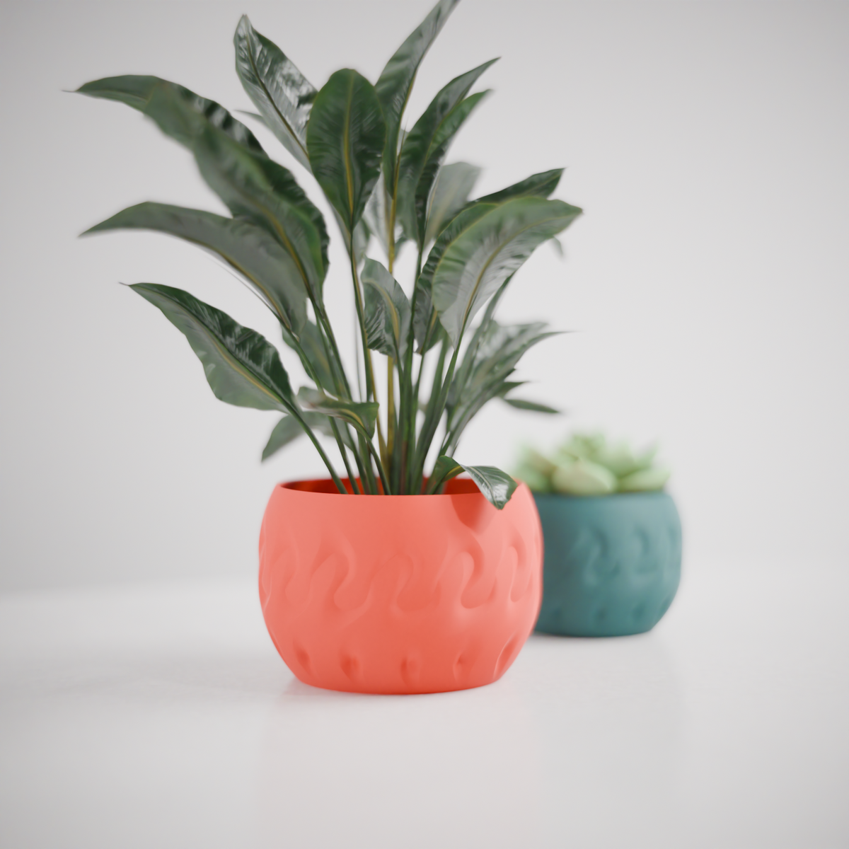 Modern Textured Planter Pot low rounded wide bowl form subtle organic flame-dent surface impressions coral red matte finish tropical plant peace lily teal green smaller planter succulent white studio background editorial hero shot
