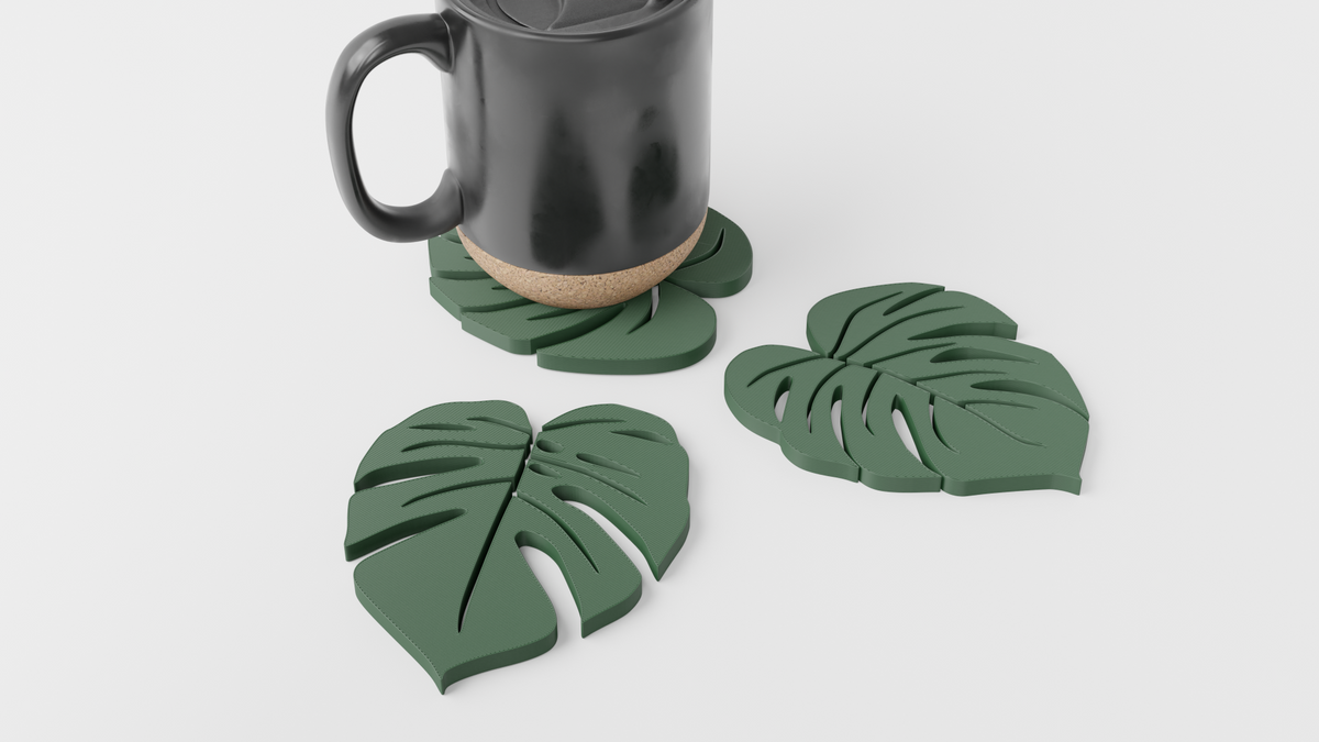 Sage green monstera leaf coasters with a black and cork mug