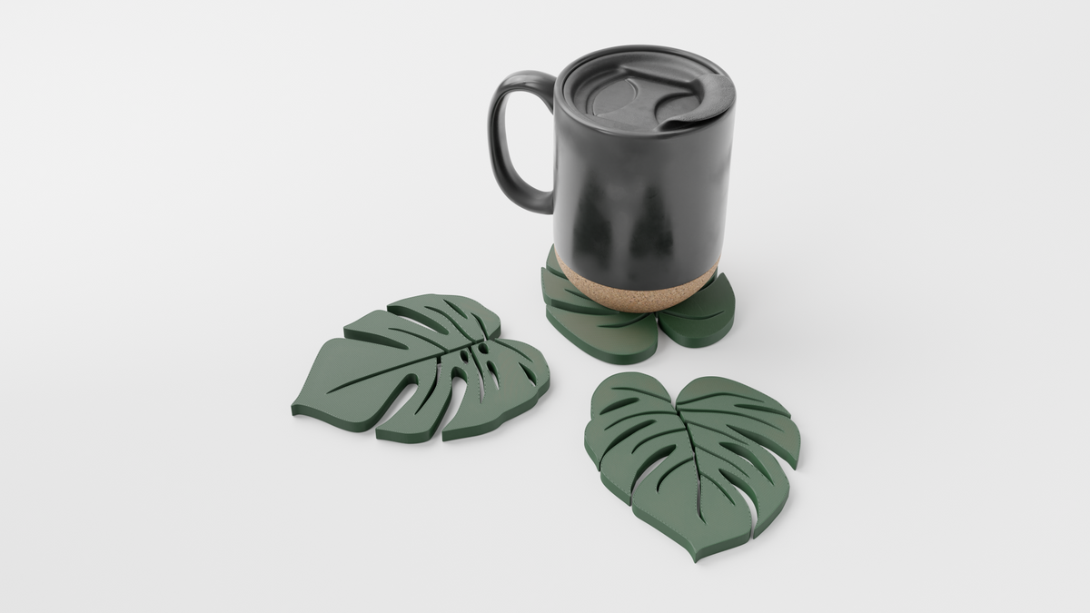 Green monstera leaf coasters on a dark surface