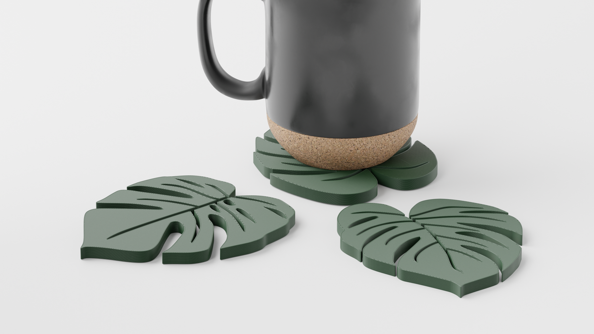 Close-up of sage green monstera leaf coasters with a cork-based mug