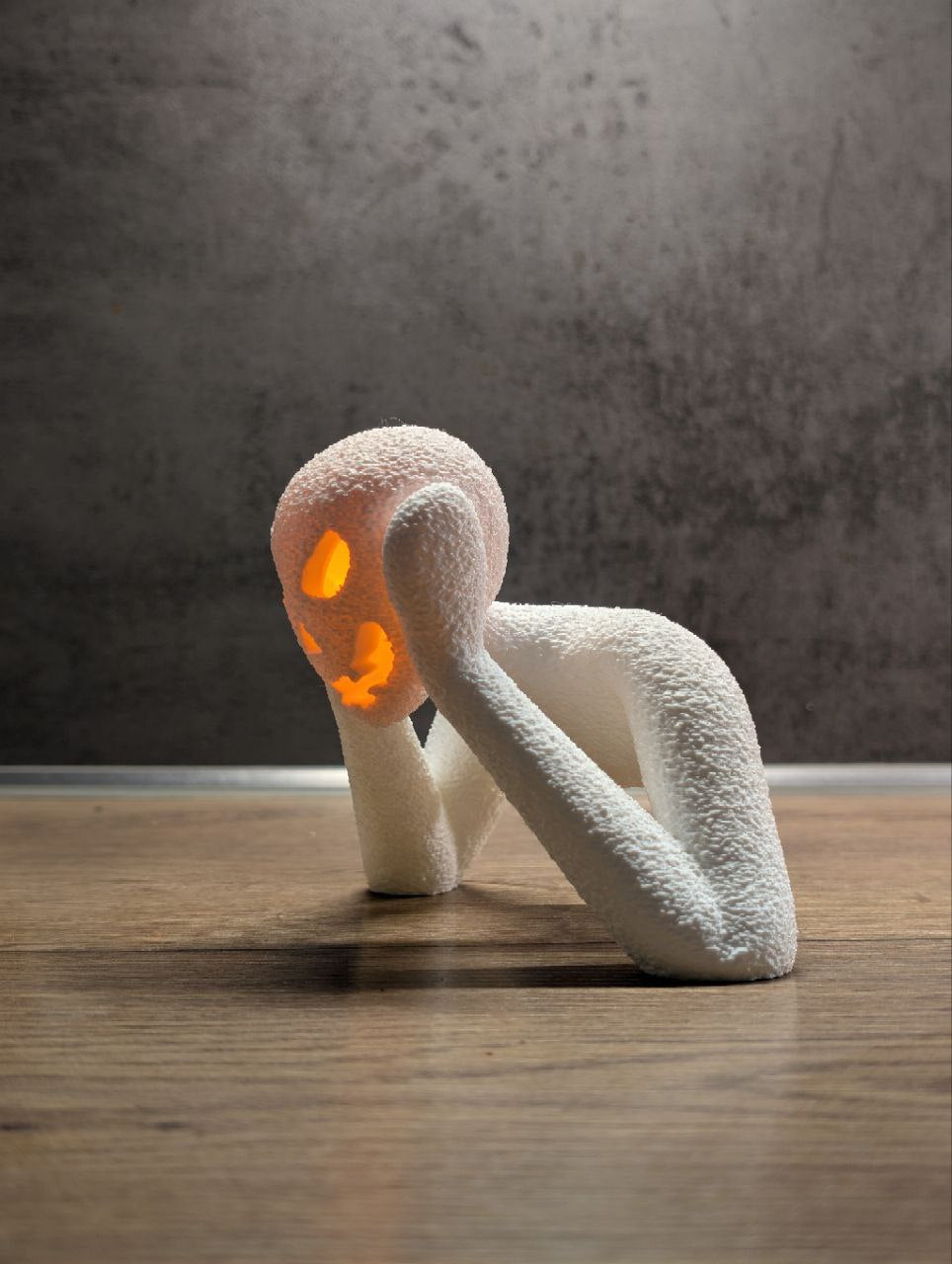 Front view of the small white NOBODY LANTERN glowing on a wooden surface